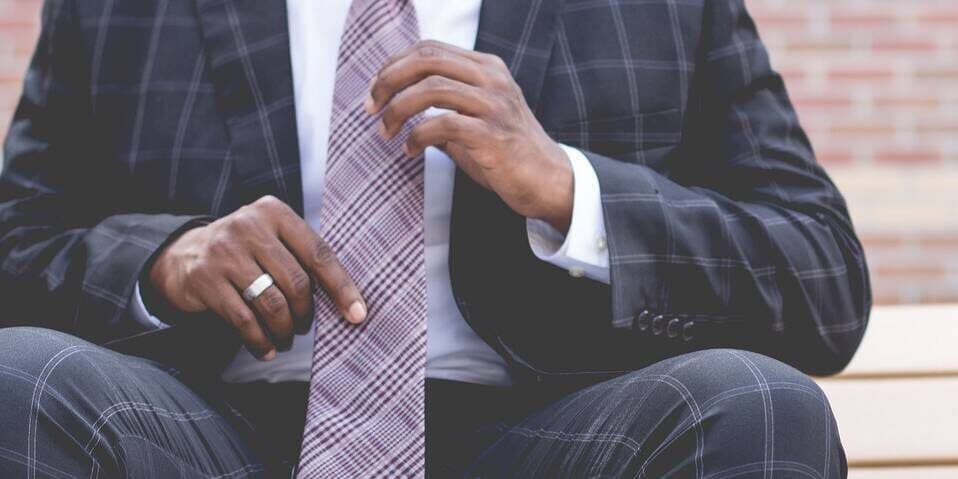 Main in suit adjusting tie.